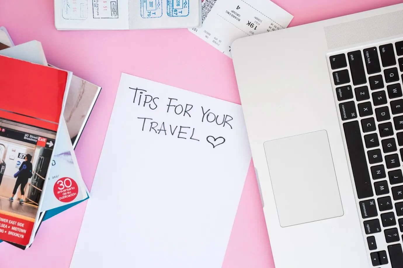 Top-down view of a laptop surrounded by travel items.