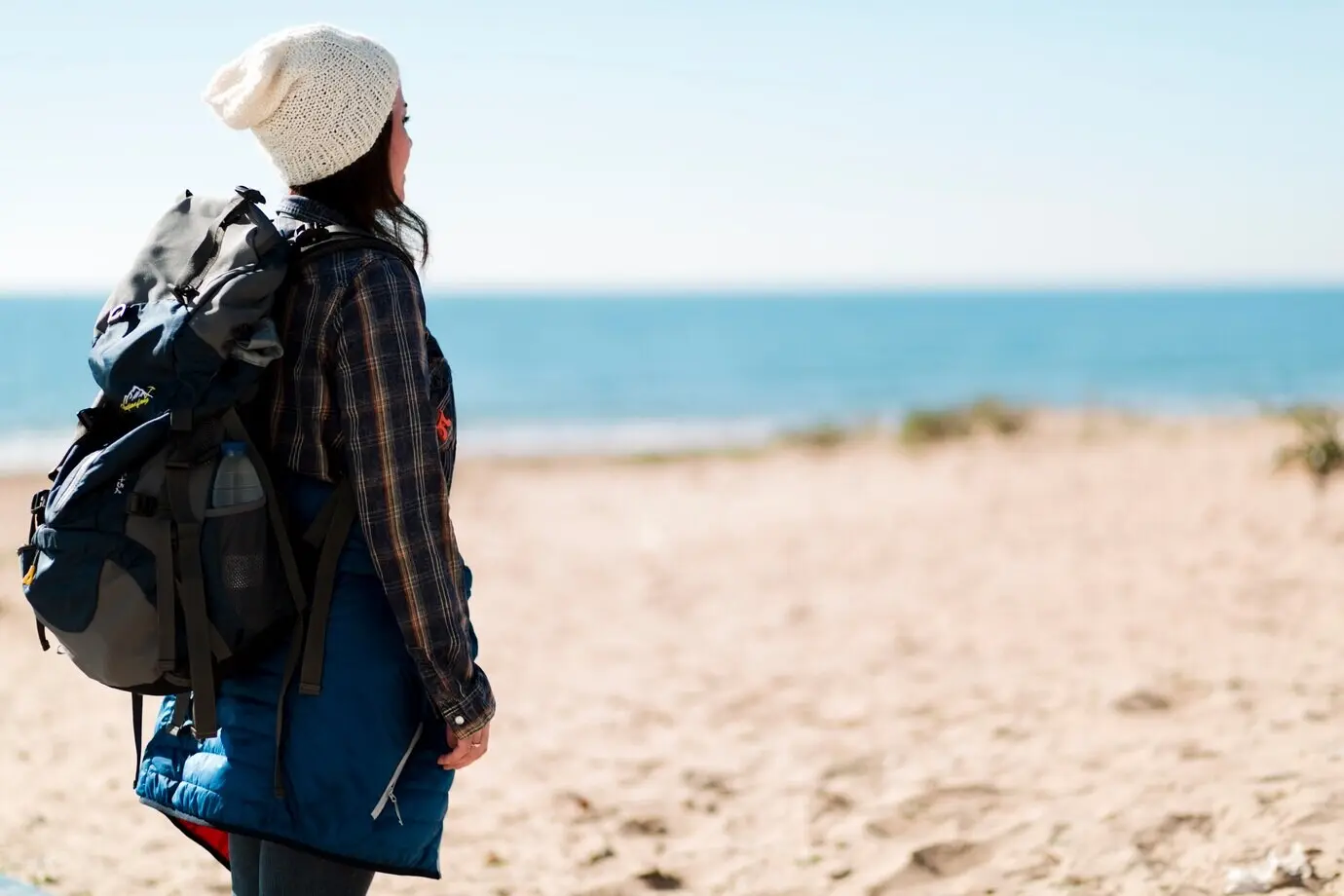 Side view of a woman standing on a beach.